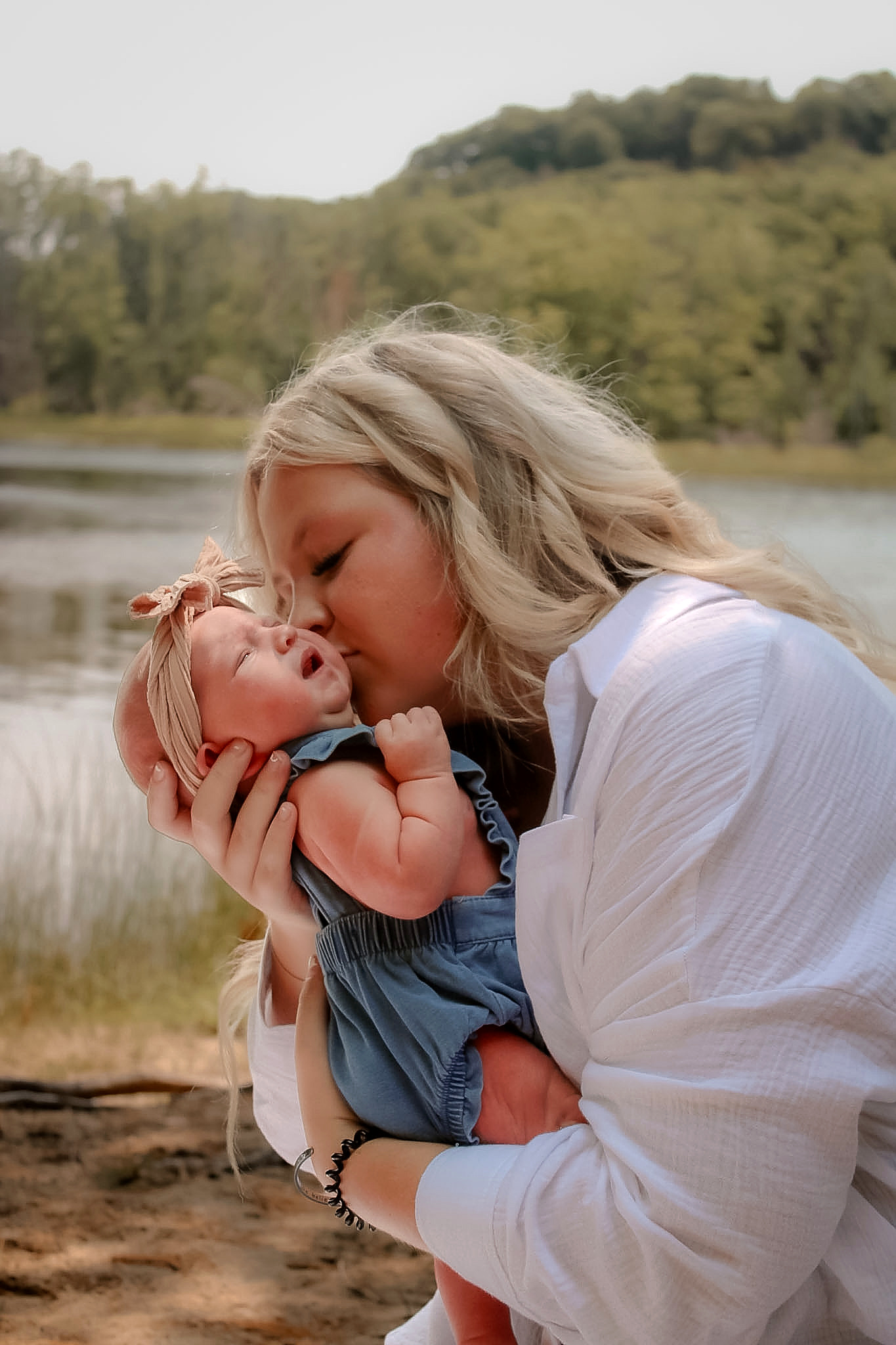 Mother kissing her newborn in warm natural light
